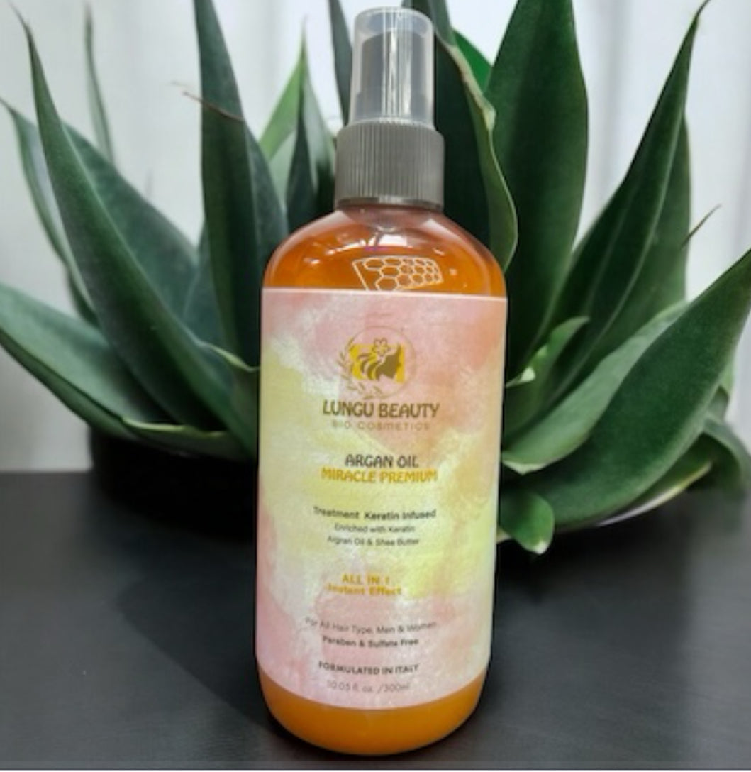 Keratin infused hair treatment bottle with argan oil and shea butter placed among green plants.