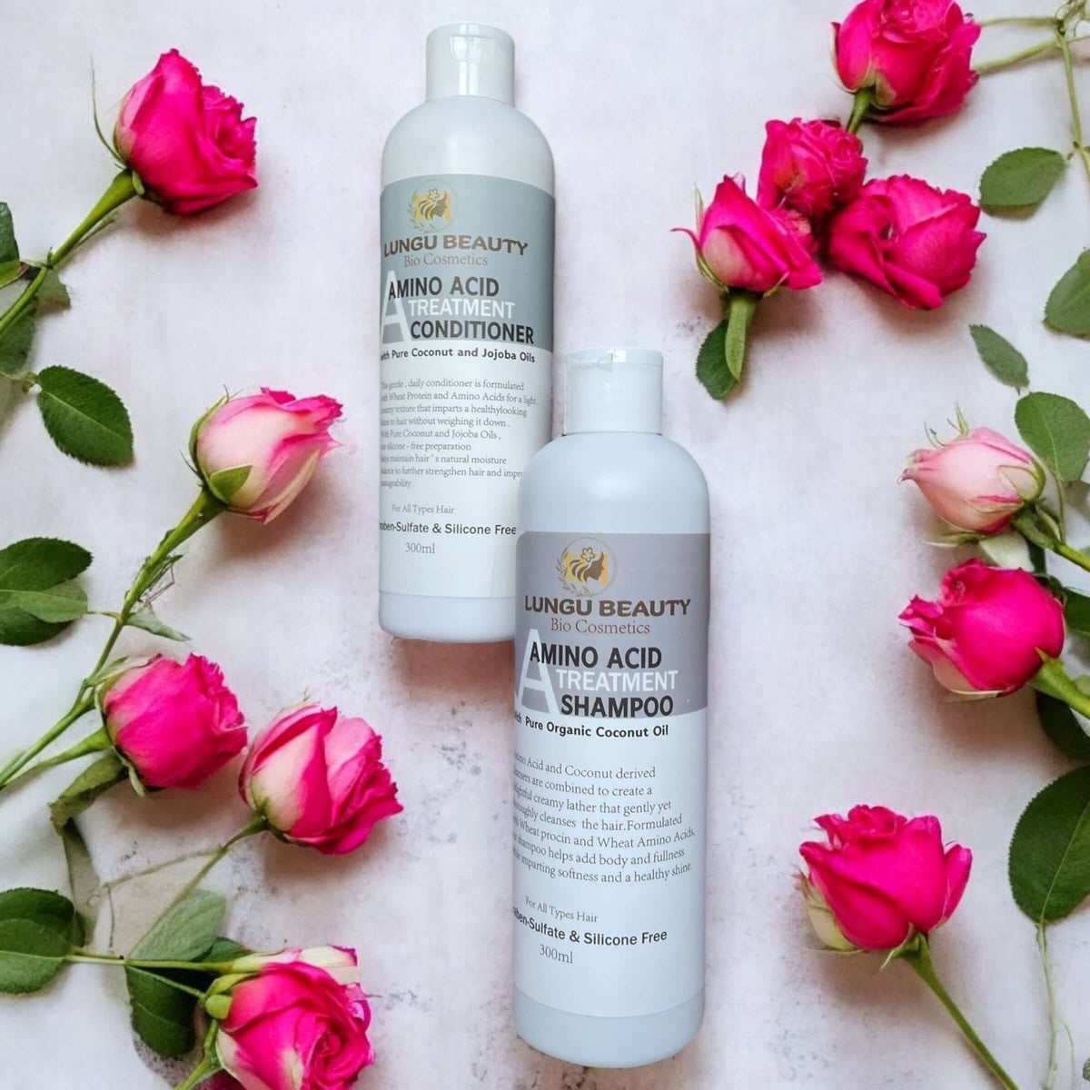 Amino acid shampoo and conditioner set with coconut and jojoba oils among pink roses.