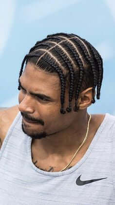 Our Services | Braids & Hair Extensions - man with braided hairstyle showcasing professional braiding technique.